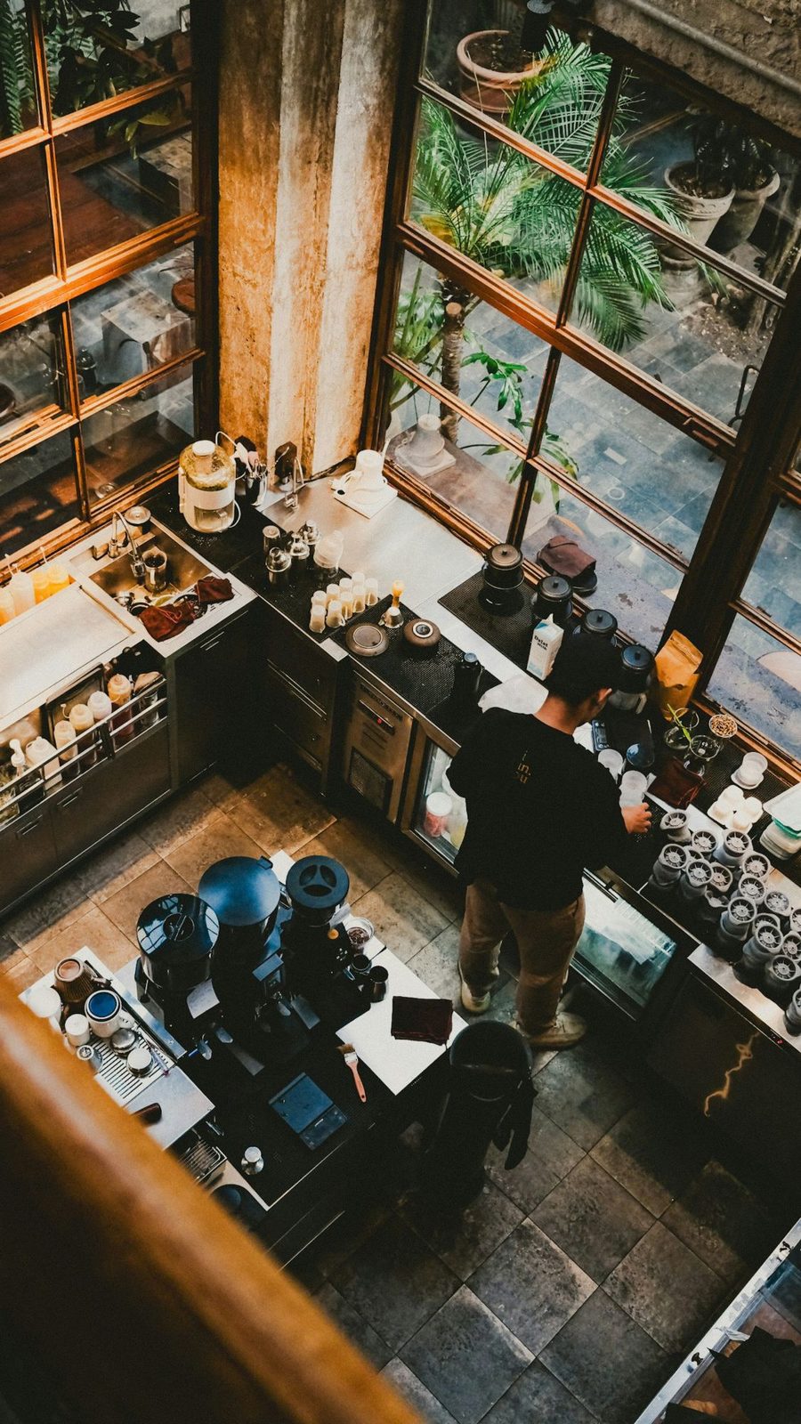 A barista making coffee behind the counter of a café, seen from above